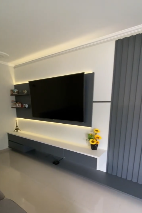 Sala de TV com painel ripado e TV 70 polegadas executada conforme a modelagem do projeto